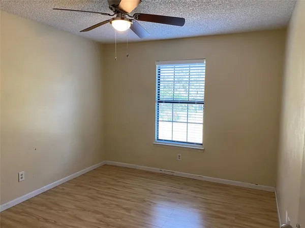 an empty room with wooden floor a ceiling fan and fan