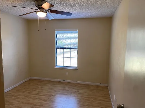 an empty room with wooden floor fan and windows