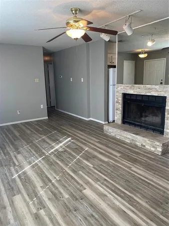 a view of a livingroom with a fireplace a ceiling fan and wooden floor
