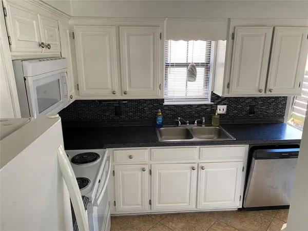 a kitchen with white cabinets and black appliances