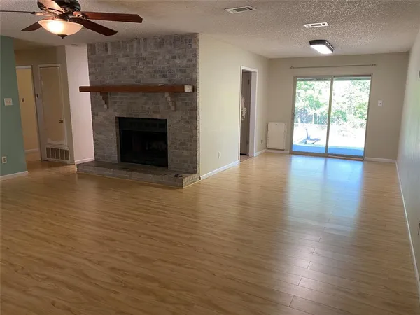 an empty room with wooden floor fireplace and windows