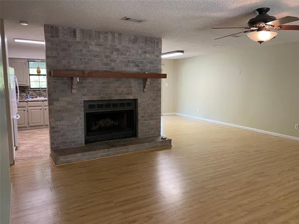 an empty room with wooden floor fireplace and windows