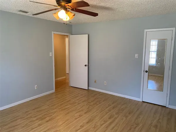a view of an empty room with window and wooden floor
