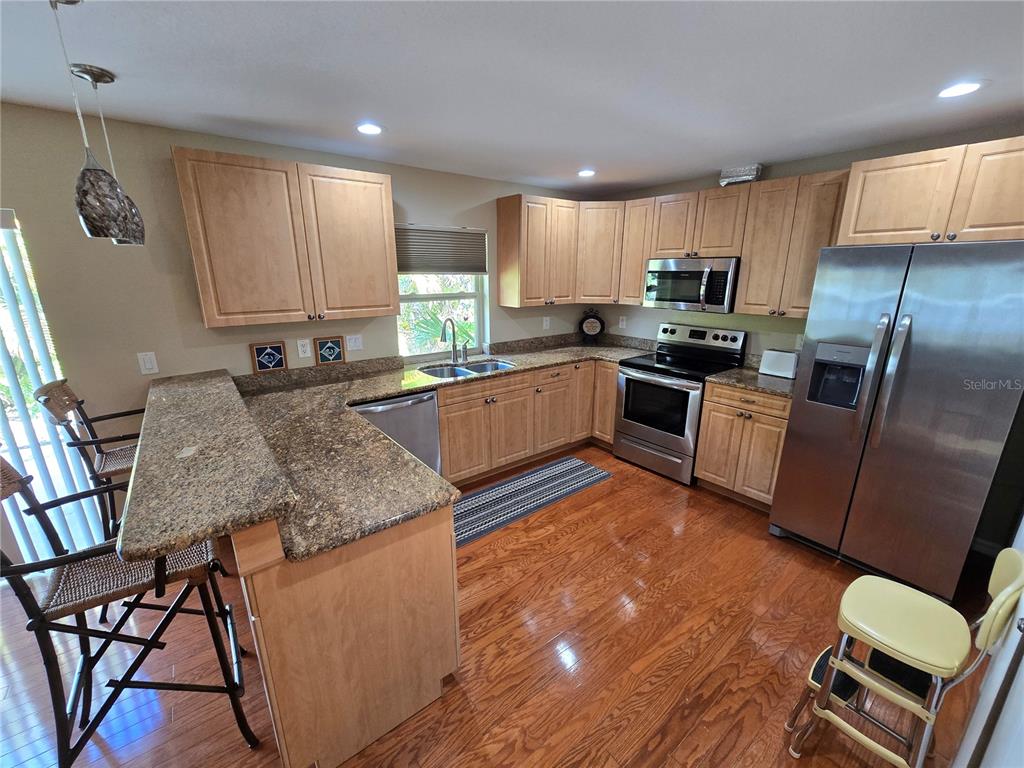 22200 Oneida Avenue Port Charlotte, FL 33952 - Photo 4 of 26 a kitchen with stainless steel appliances granite countertop a sink dishwasher stove refrigerator dining table and chairs