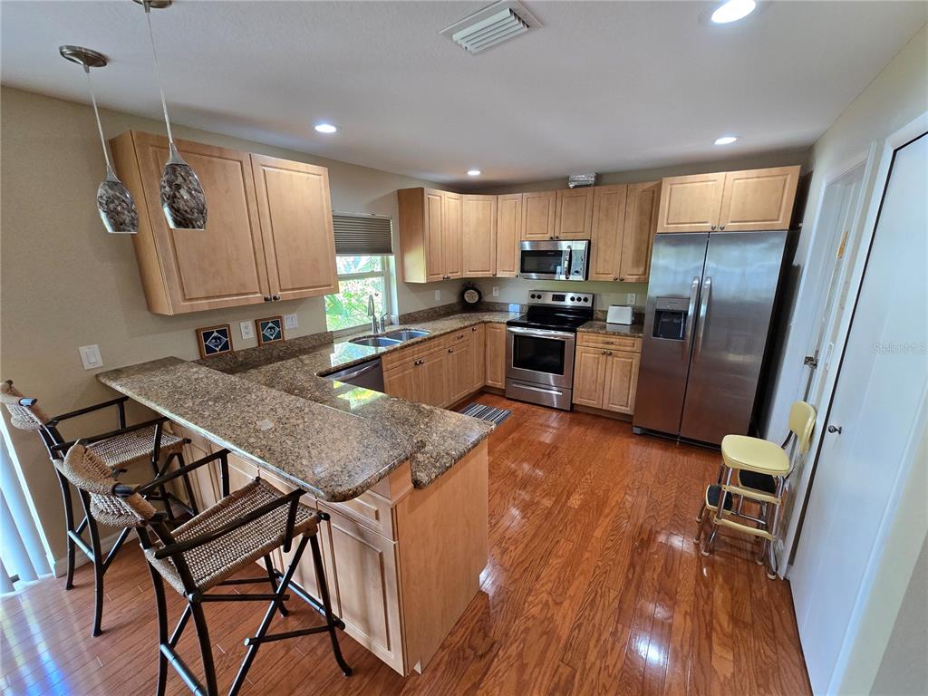 22200 Oneida Avenue Port Charlotte, FL 33952 - Photo 7 of 26 a kitchen with granite countertop a table chairs refrigerator and wooden floor
