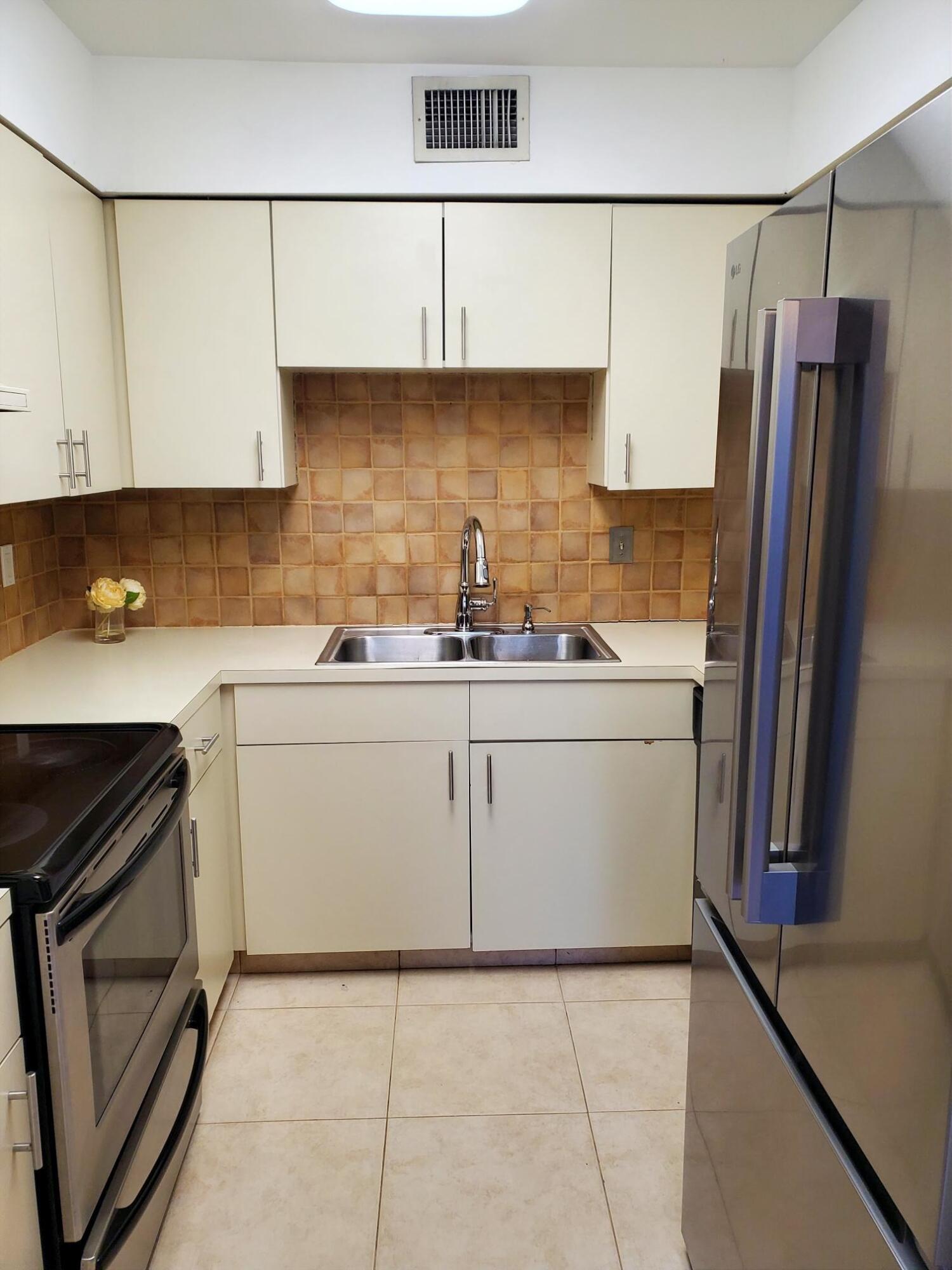 2445 Southwest 22nd Avenue, Unit 1020 Delray Beach, FL 33445 - Photo 12 of 37 a kitchen with a sink a stove and refrigerator