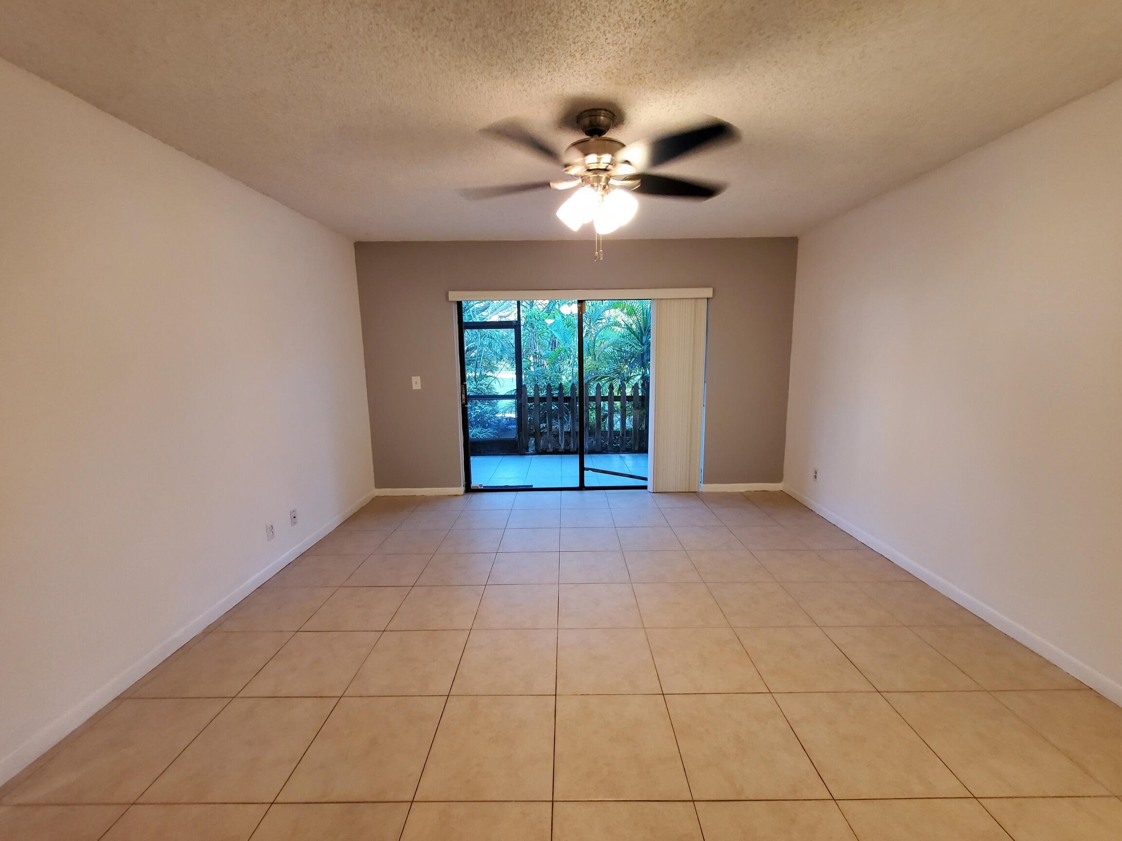 2445 Southwest 22nd Avenue, Unit 1020 Delray Beach, FL 33445 - Photo 29 of 37 a view of an empty room with a chandelier fan and window