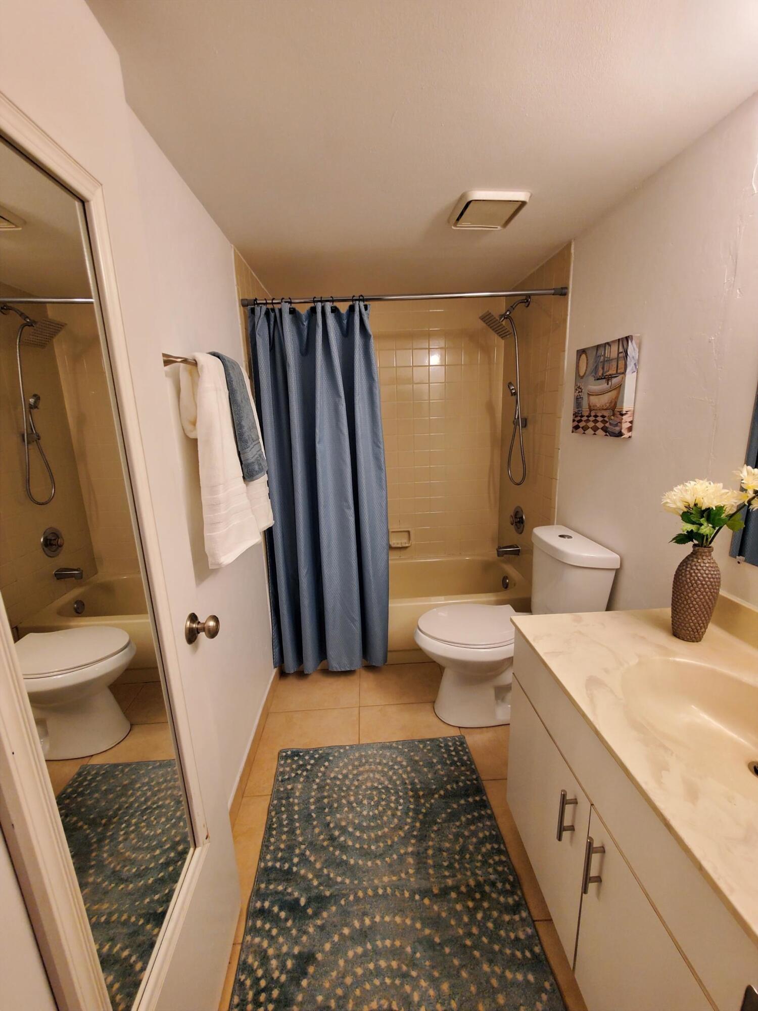 2445 Southwest 22nd Avenue, Unit 1020 Delray Beach, FL 33445 - Photo 31 of 37 a bathroom with a sink a toilet a mirror and shower