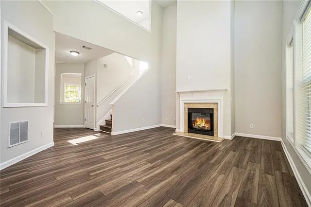 a view of an empty room with wooden floor fireplace and a window