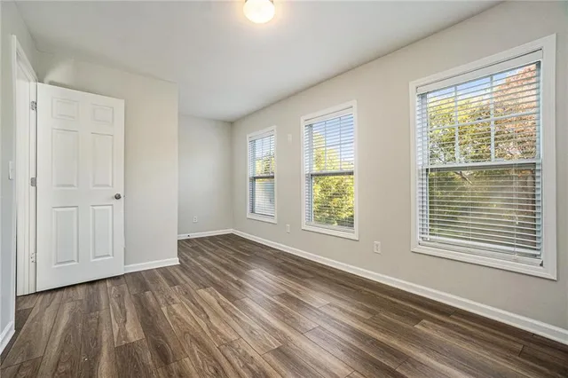 a view of an empty room with wooden floor and a window
