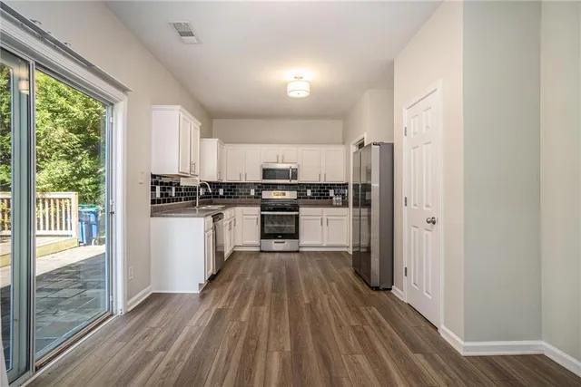 a kitchen with kitchen island wooden floors appliances and window