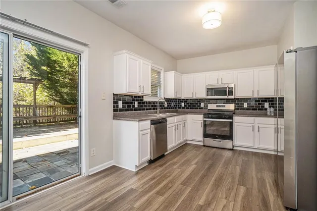 a kitchen with white cabinets and appliances
