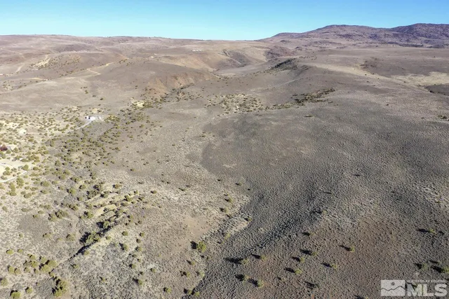 a view of a dry field with mountains in the background