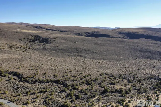 a view of a dry field with mountains in the background