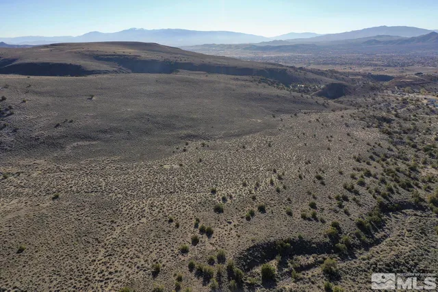 a view of a dry field with mountains in the background