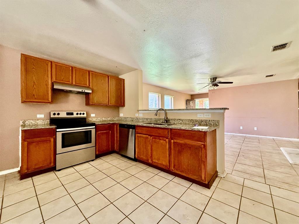 1144 Switchgrass Lane Crowley, TX 76036 - Photo 3 of 17 a kitchen with granite countertop a stove a sink and a microwave