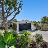 a front view of a house with a yard large tree and a wooden fence