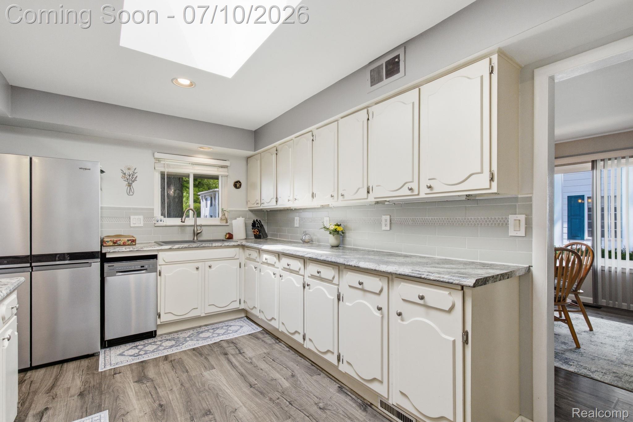 1501 River Road, Unit 301 St. Clair, MI 48079 - Photo 8 of 32 Kitchen featuring white cabinetry, gray countertop surfaces, a light-toned tile backsplash, stainless steel appliances, and wood-finish flooring