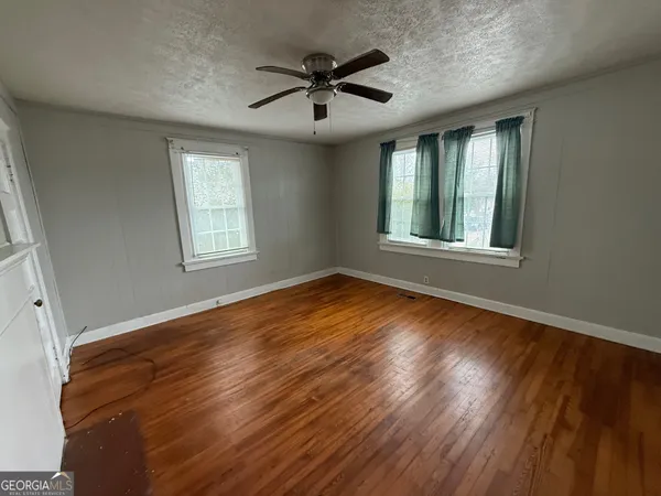 a view of empty room with wooden floor and fan