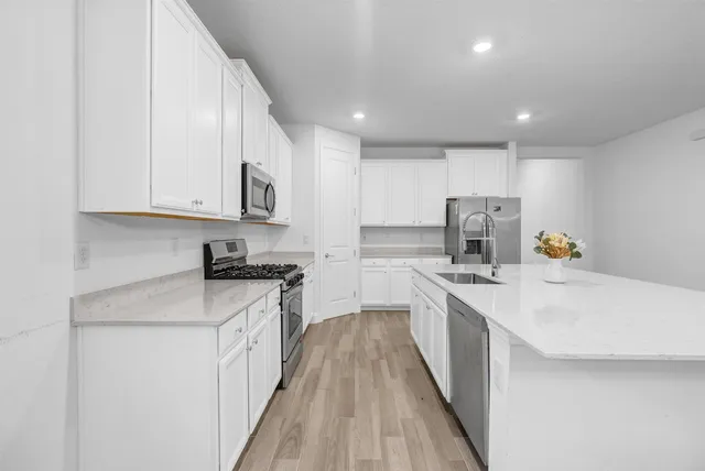 a kitchen with stainless steel appliances granite countertop a stove a sink and a microwave