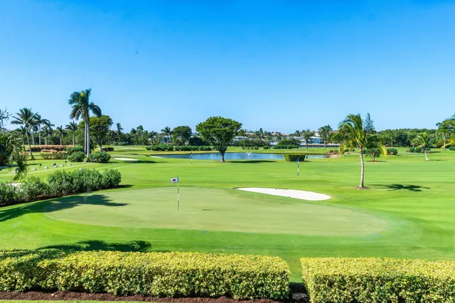 a view of a white house with a big yard plants and large trees