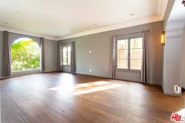 a view of an empty room with wooden floor and windows