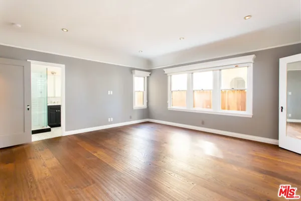 an empty room with wooden floor and windows