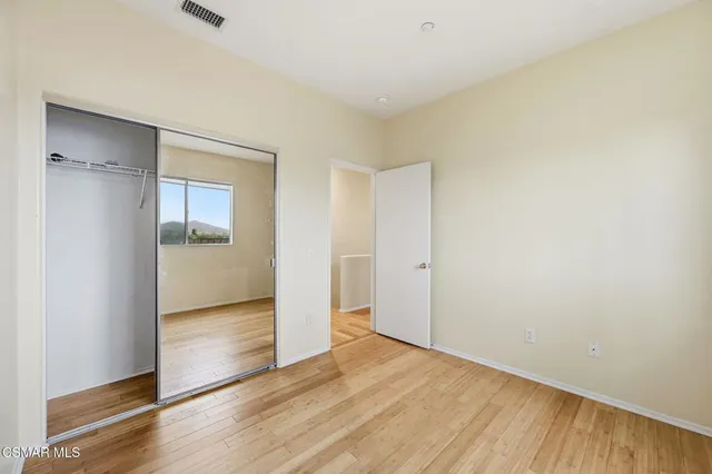 an empty room with wooden floor & windows
