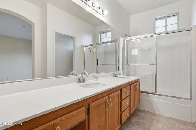 a bathroom with a double vanity sink and mirror with shower