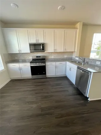 a large kitchen with granite countertop a stove a sink and a microwave