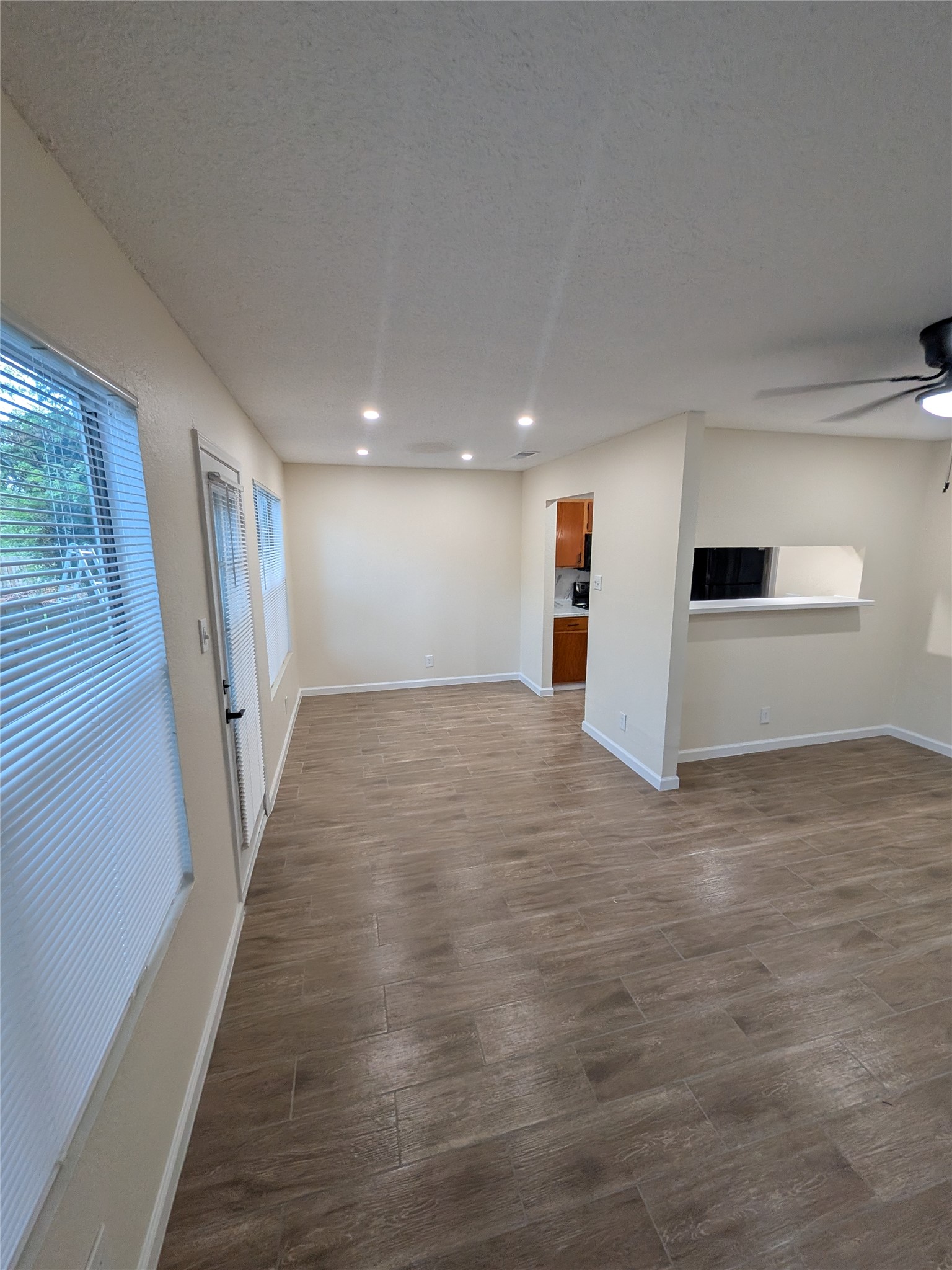 13303 Lyndhurst Street, Unit B Austin, TX 78729 - Photo 4 of 13 An inviting open-concept area featuring warm wood-look flooring and a peek into the kitchen.