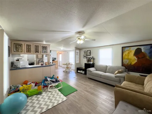 a kitchen with stainless steel appliances kitchen island granite countertop a refrigerator a stove a sink a dining table and chairs with wooden floor