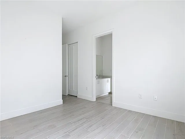 a view of an empty room with wooden floor and closet