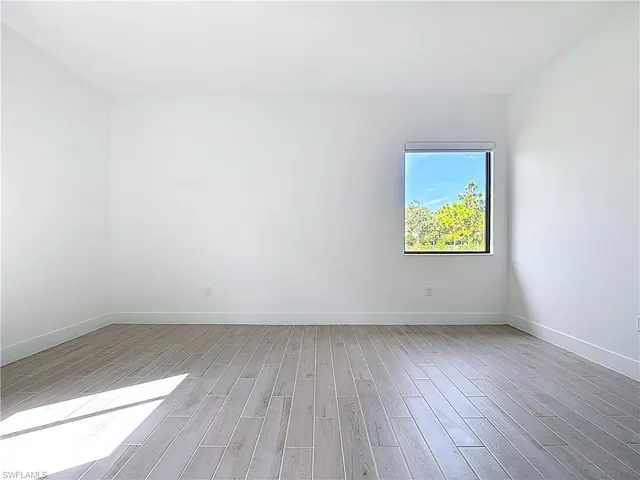 an empty room with wooden floor and a window