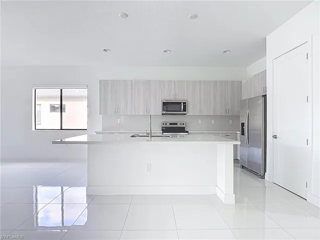 a large white kitchen with cabinets and a refrigerator