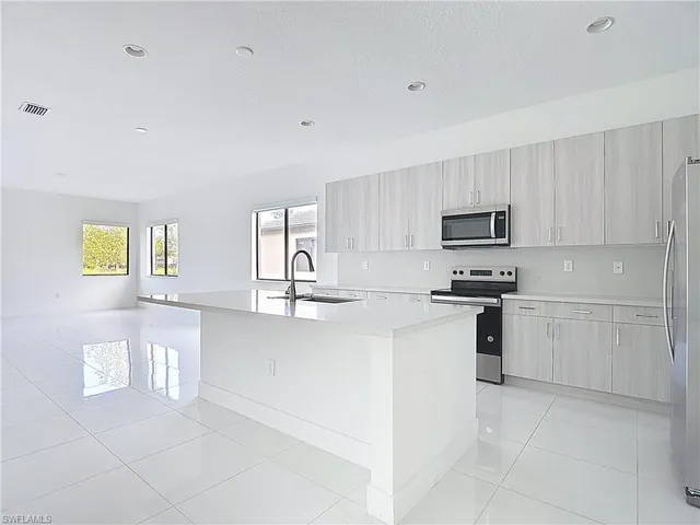 a kitchen with white cabinets and appliances