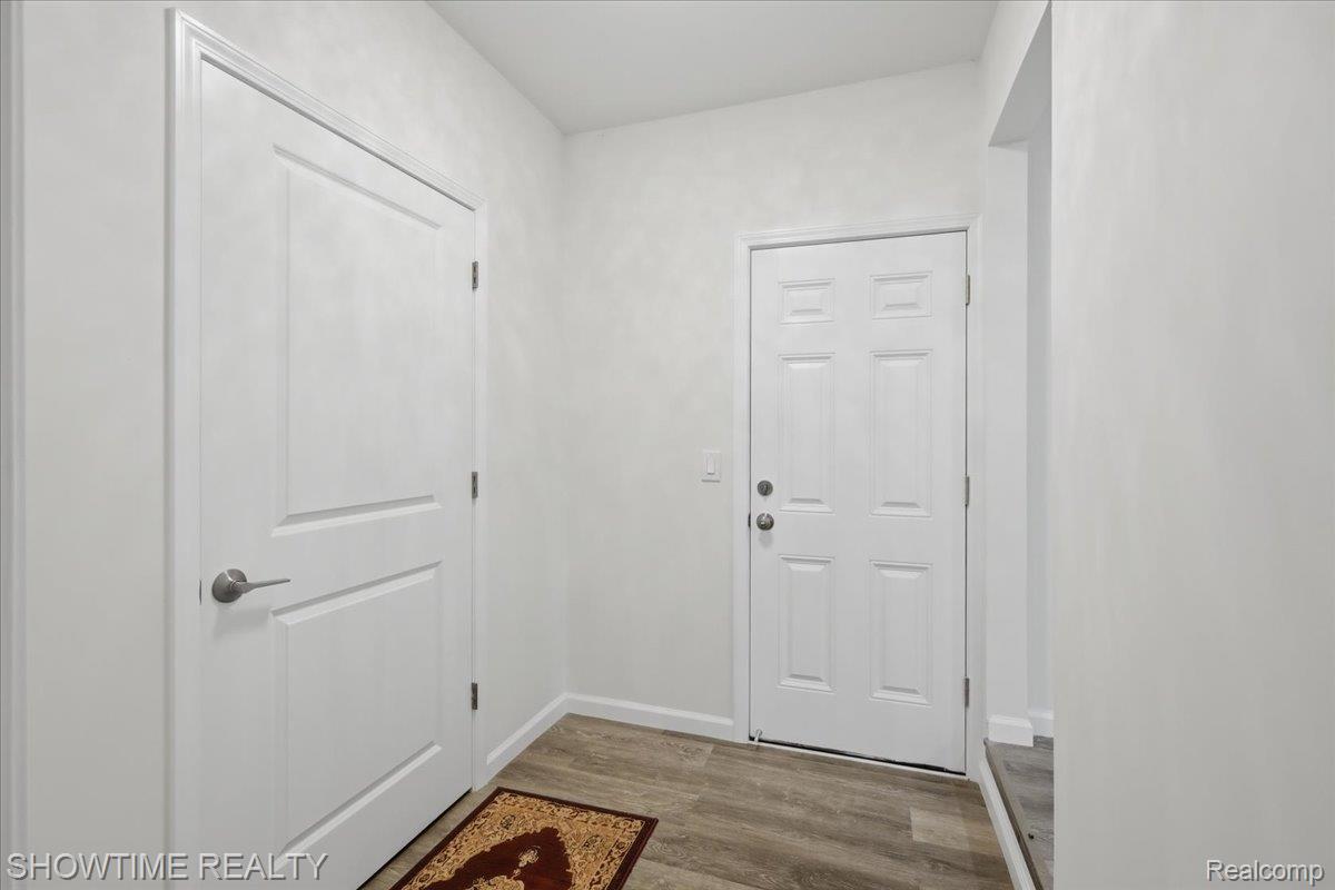 29255 Utley Road Farmington, MI 48334 - Photo 33 of 46 Wood-finish flooring with white baseboards, a paneled door with brushed nickel hardware, and a six-panel exterior door