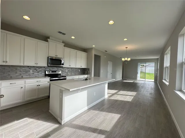 a large kitchen with stainless steel appliances lots of counter space and wooden floor