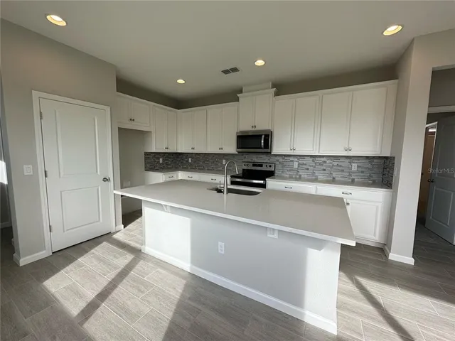 a large kitchen with kitchen island granite countertop a sink a stove a refrigerator and cabinets