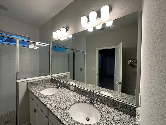 a bathroom with a granite countertop double vanity sink and a mirror
