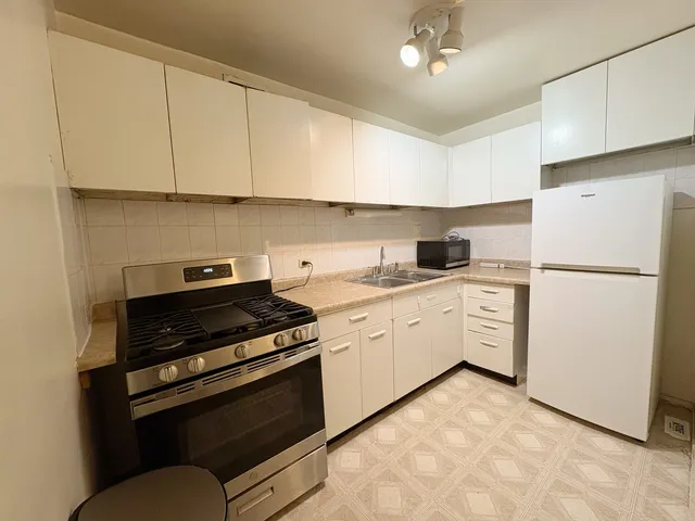 a kitchen with granite countertop a refrigerator a stove a sink dishwasher and white countertops with wooden floor