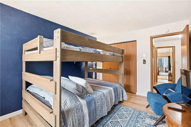 a view of a large white house with a large tree and wooden fence