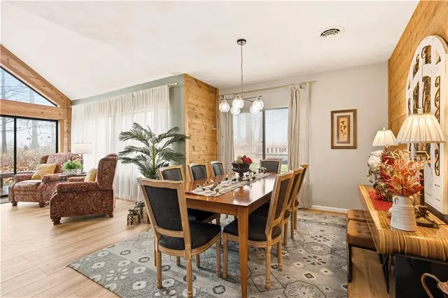 a kitchen with stainless steel appliances granite countertop a stove a refrigerator a oven a sink a dining table and chairs with wooden floor