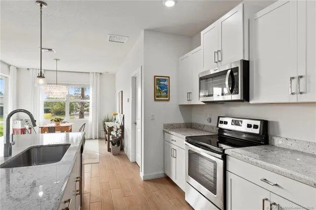 a kitchen with stainless steel appliances a stove a sink a microwave a refrigerator a stove and cabinets