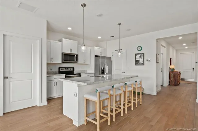 a large kitchen with white cabinets stainless steel appliances a dining table and chairs