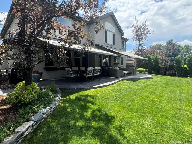 a view of a white house with a big yard plants and large trees
