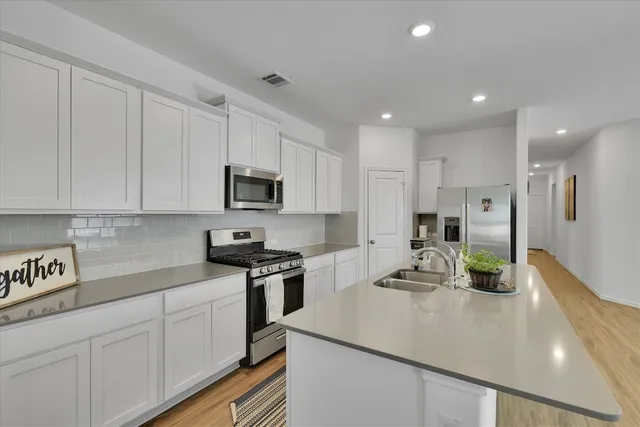 a kitchen with a sink stainless steel appliances and white cabinets