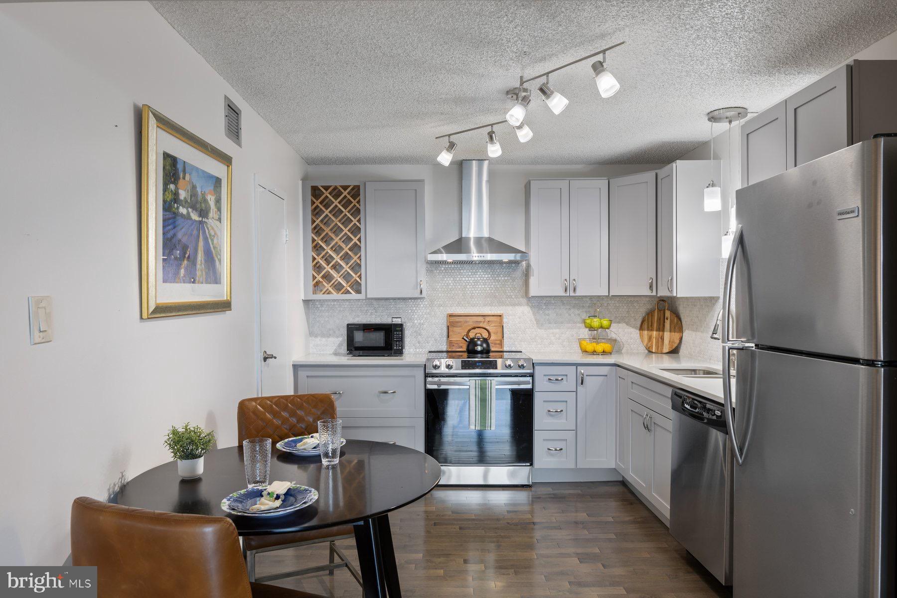 205 East Joppa Road, Unit 2403 Towson, MD 21286 - Photo 12 of 48 a kitchen with a refrigerator a stove a sink dishwasher and white cabinets with wooden floor