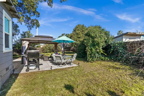 a view of a patio with table and chairs under an umbrella with a fire pit