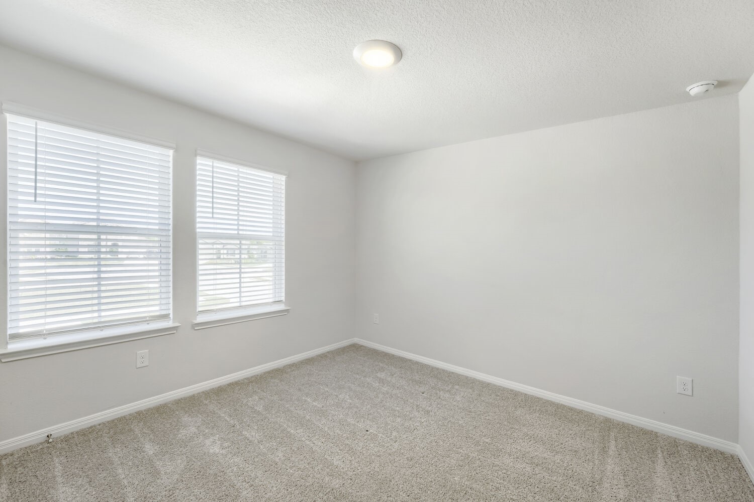 13507 Howser Trace Manor, TX 78653 - Photo 18 of 28 A well-lit bedroom with two bright windows and soft carpet awaits your personal touch.